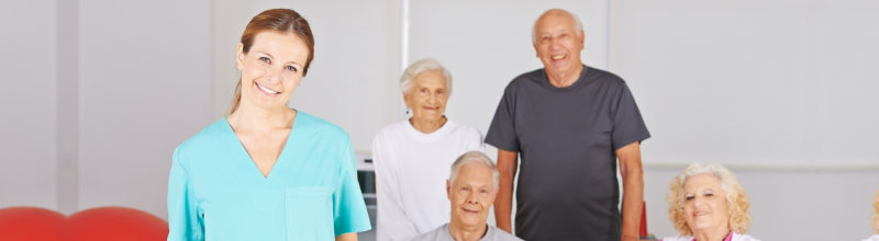 group of elderly patients and caregiver smiling